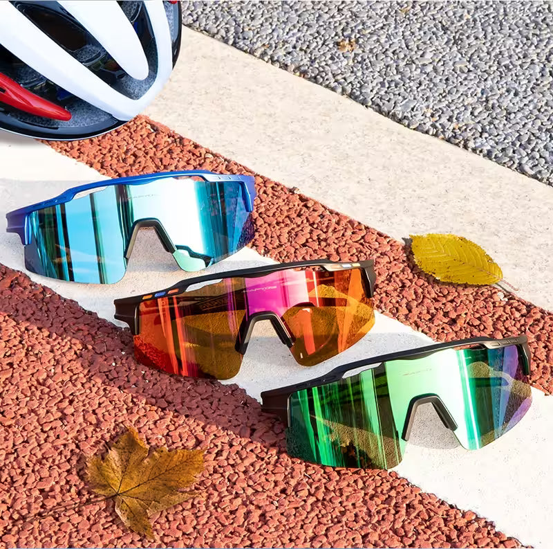 Three pairs of colorful sunglasses on a textured surface with a helmet in the background.