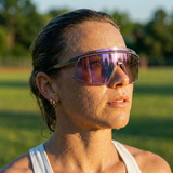 Person wearing reflective sunglasses outdoors with a blurred natural background