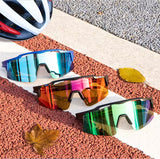 Three pairs of colorful sunglasses on a textured surface with a helmet in the background.